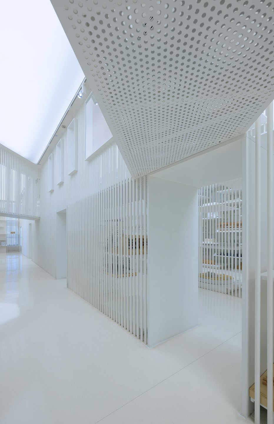 Spazio architettonico moderno con divisori a doghe bianche e luci a soffitto brillanti.